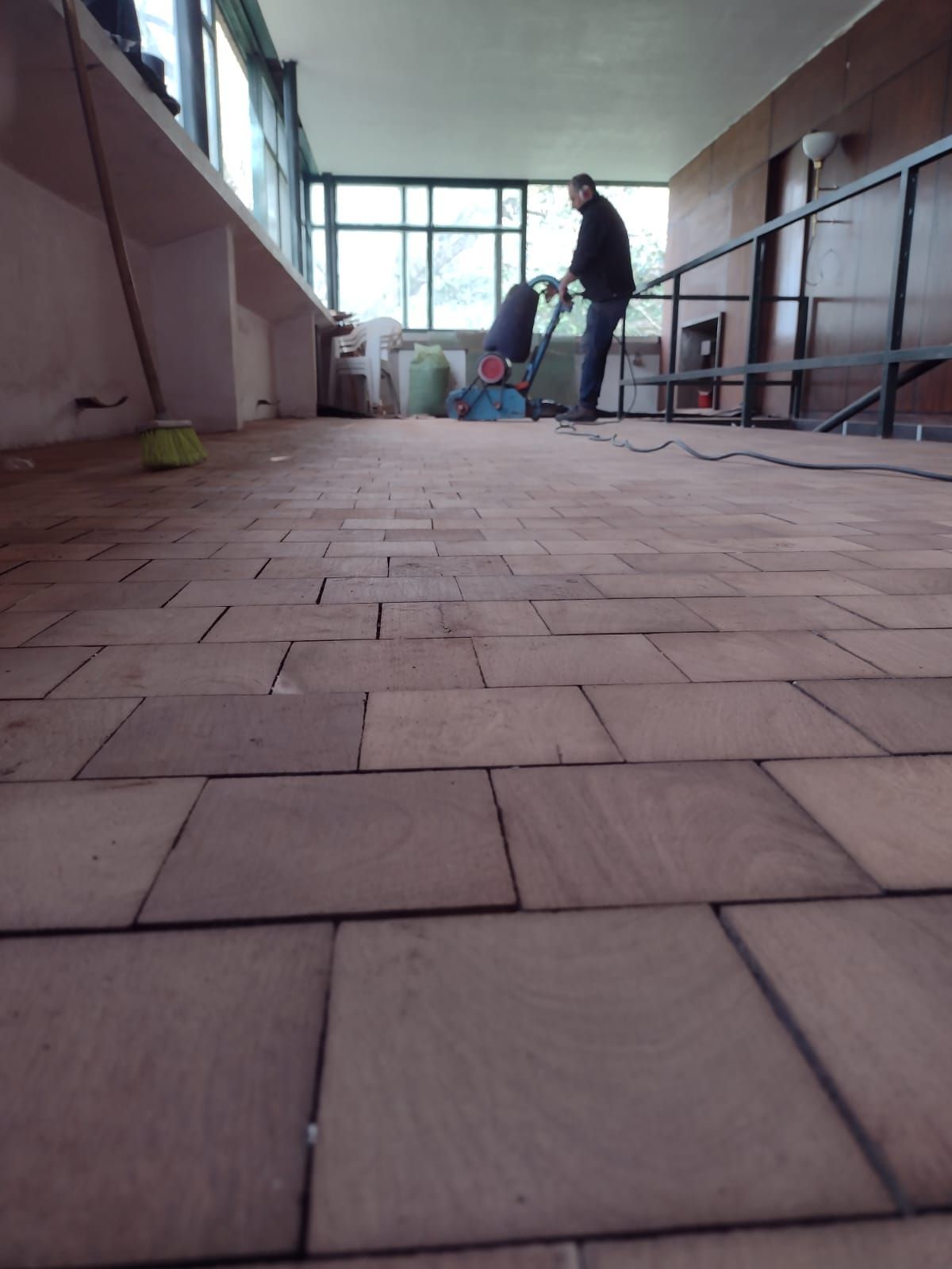 Un hombre está limpiando un piso de ladrillo con una aspiradora.