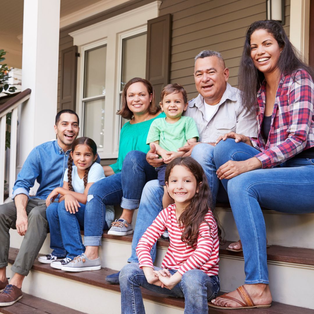 Family sitting on porch steps, smiling.