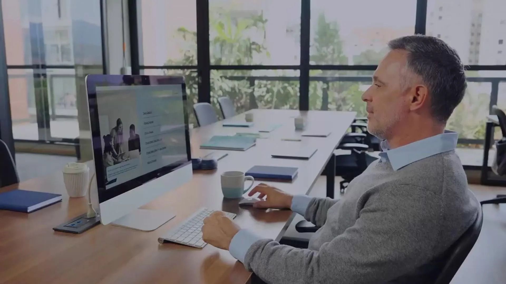 Man at computer in office, attending video call, hands on keyboard and mouse.