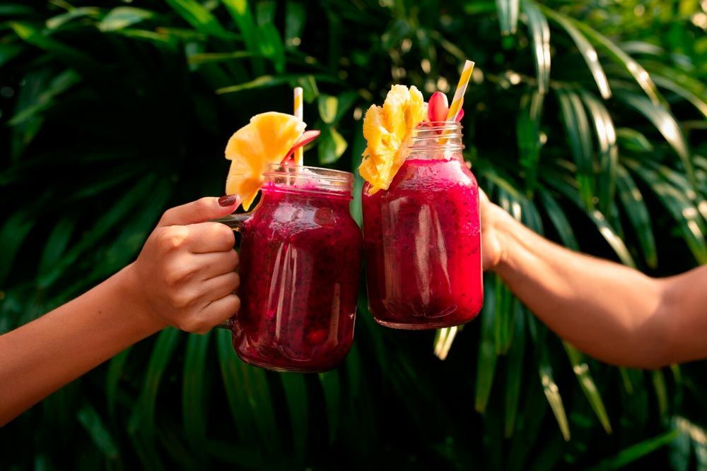 Two people are toasting with smoothies in mason jars.
