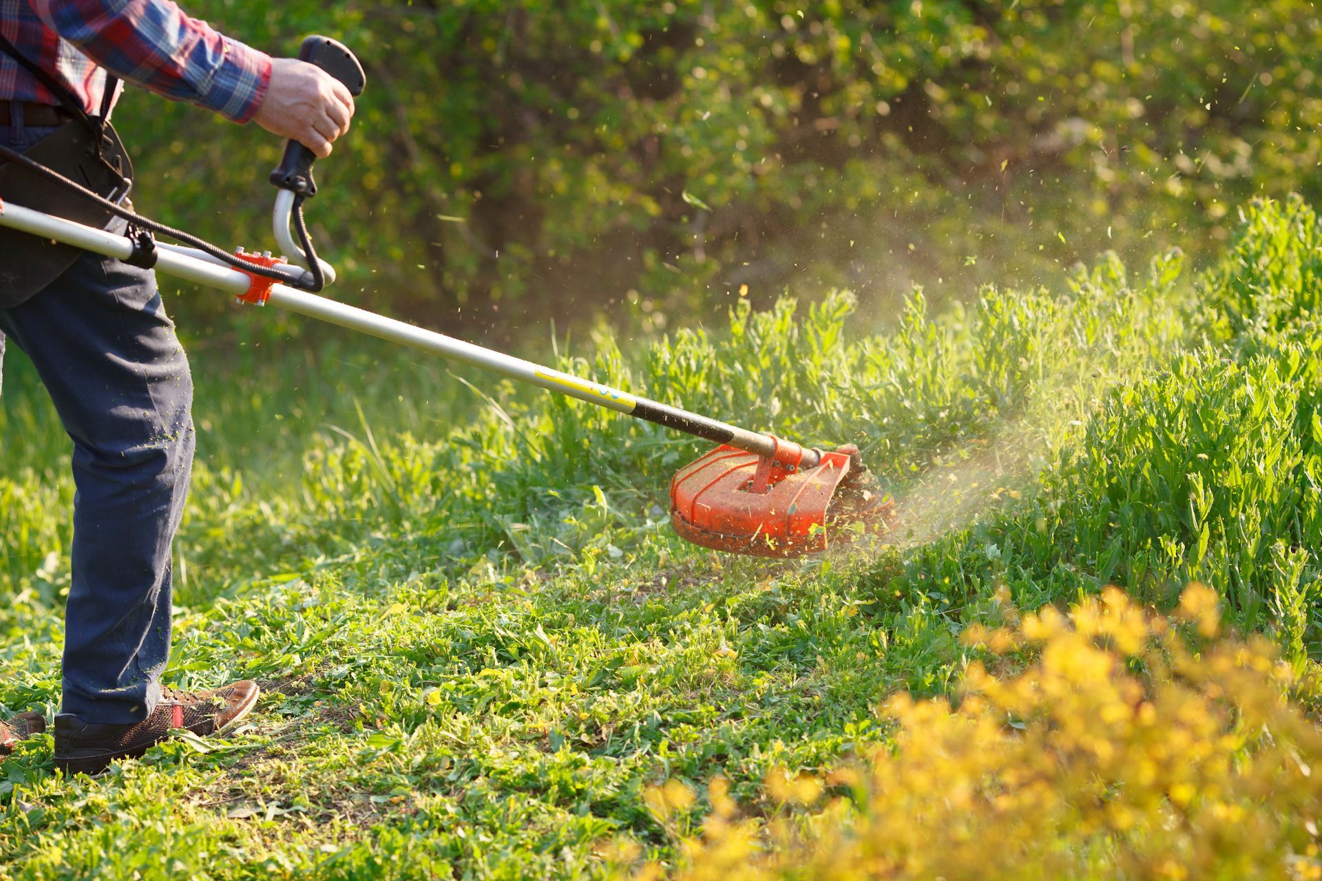 A man is mowing the grass with a lawn mower.