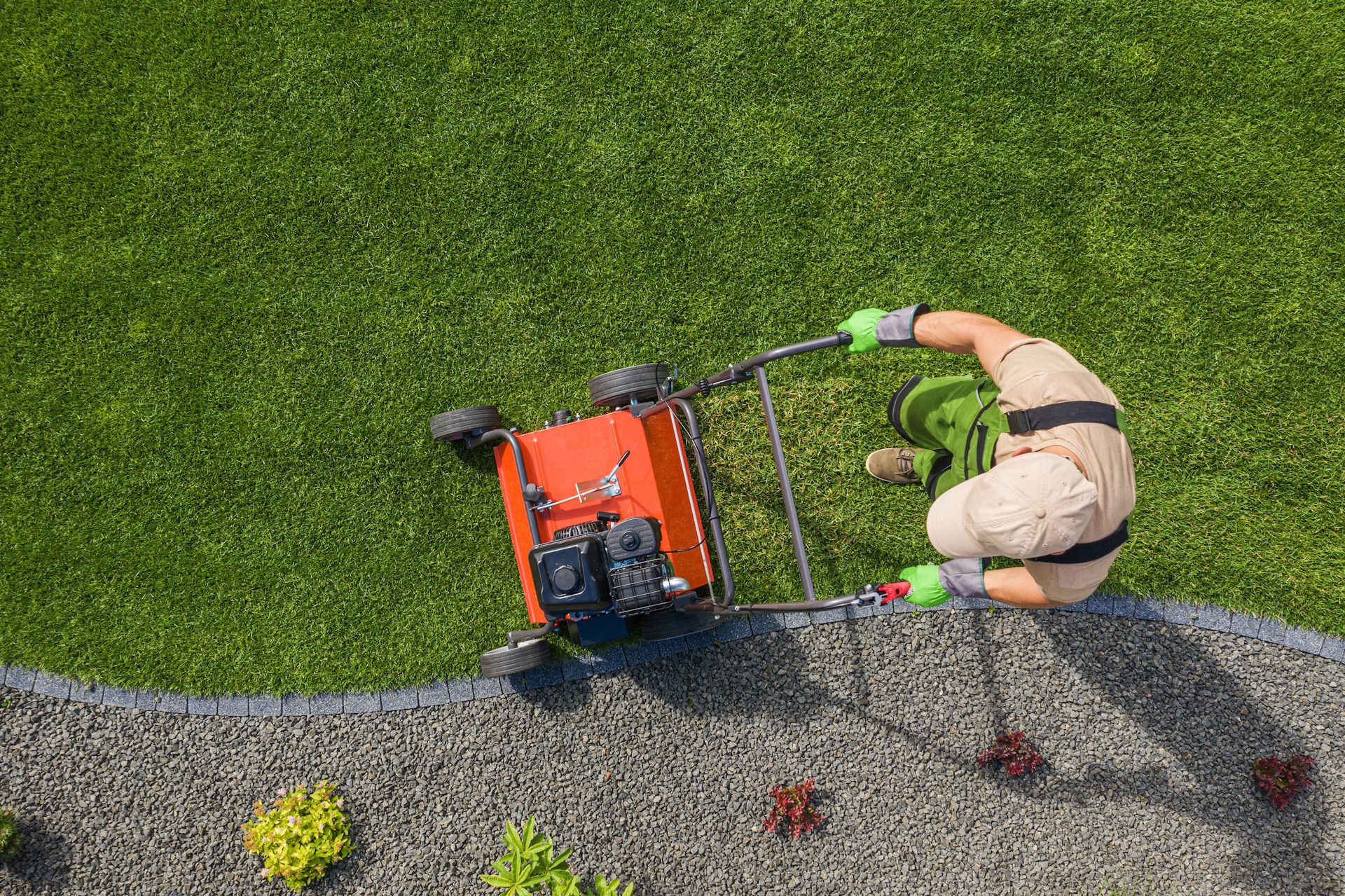 An aerial view of a man using a lawn mower on a lush green lawn.