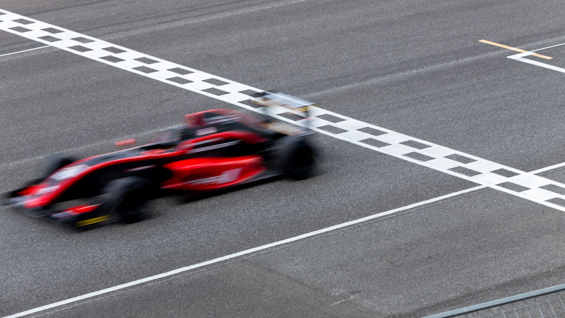 Old wooden mill with water flowing, surrounded by trees and a gravel path.