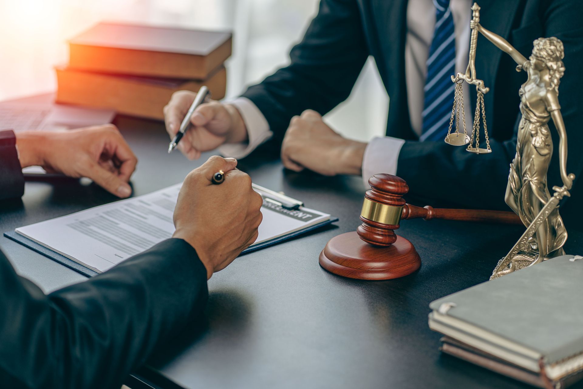 Two men are sitting at a table with a statue of justice and a gavel.