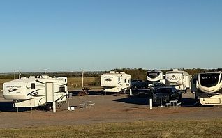 RV trailers parked on a roadside lot under a clear blue sky