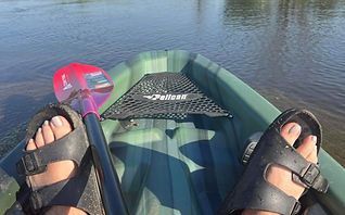 View from a kayak with feet in sandals, paddle, and calm water ahead