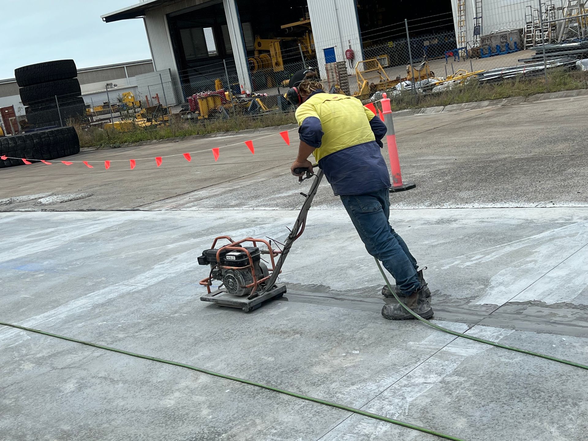 Worker Using a Vibrating Plate Compactor on Concrete in an Industrial Setting — Ablecut Concrete Cutting & Coring In East Mackay, QLD