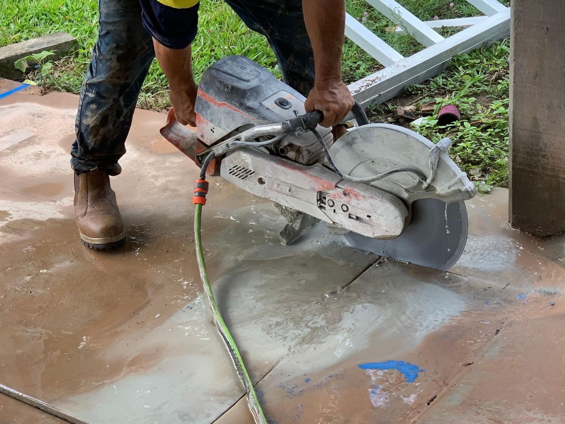 Worker using a concrete saw to cut a wet floor slab near a pillar. — Ablecut Concrete Cutting & Coring In East Mackay, QLD