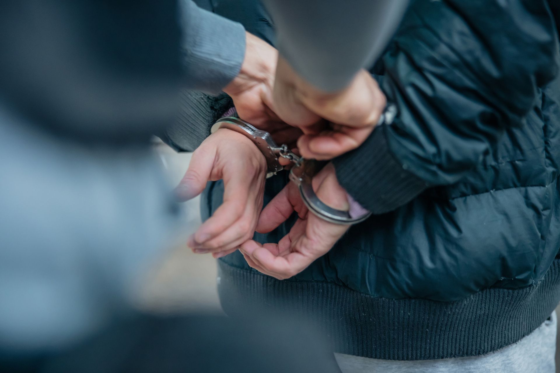 Person in handcuffs, being arrested. A person's hands are cuffed behind their back. Person in handcuffs, being arrested. A person's hands are cuffed behind their back.