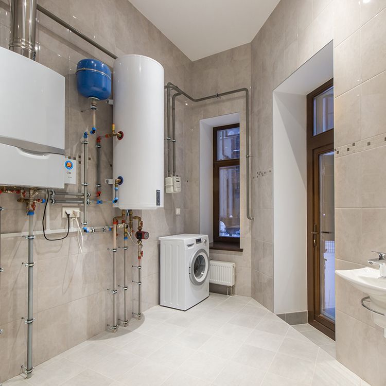 A utility room with a washing machine, water heater, and heating equipment installed on light-colored walls.