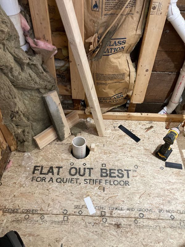 Shower floor under construction with drain pipe and wooden supports.
