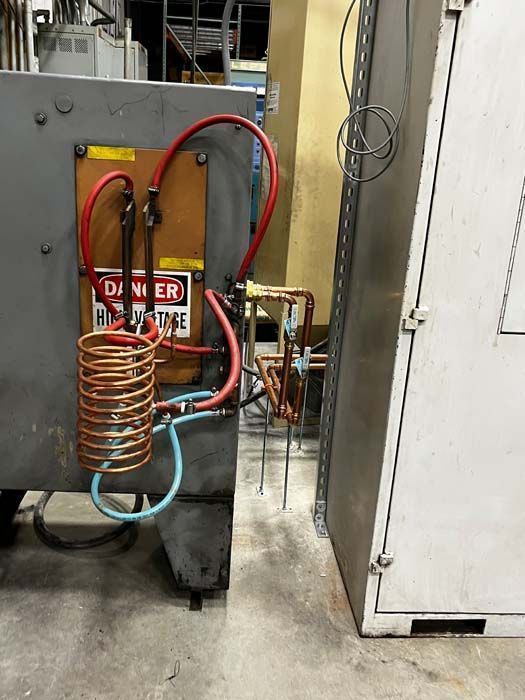 Gray industrial equipment with copper coils and electrical wiring. A 