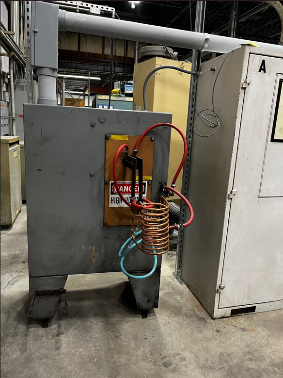 Industrial machine with copper coils, electrical wiring, and a warning sign.