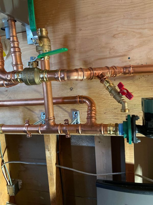 Copper pipes and valves against a wooden wall; a water system.