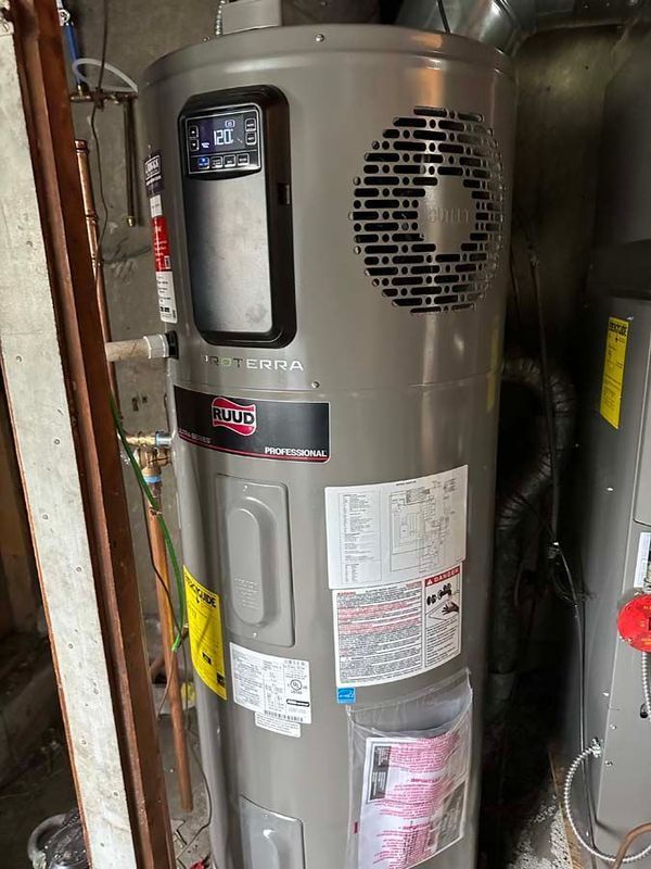 Tall, grey electric water heater with digital display, installed in a utility room.