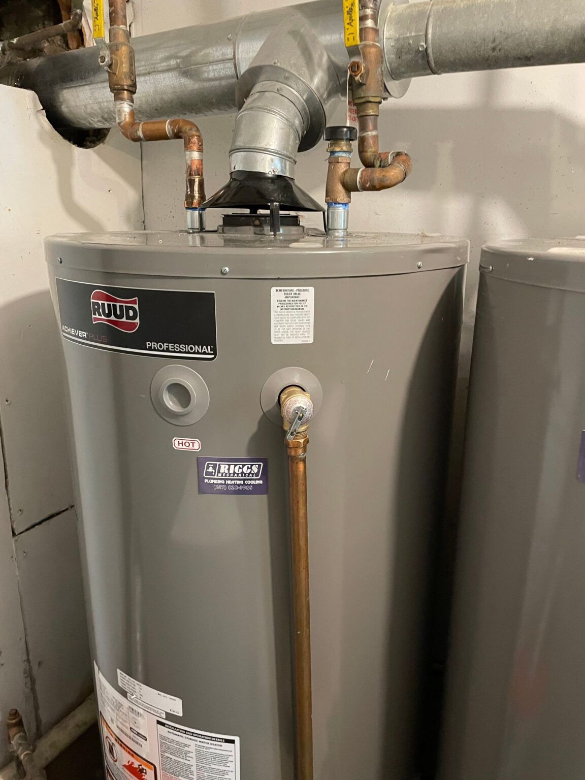 Gray water heater with copper pipes in a utility room.