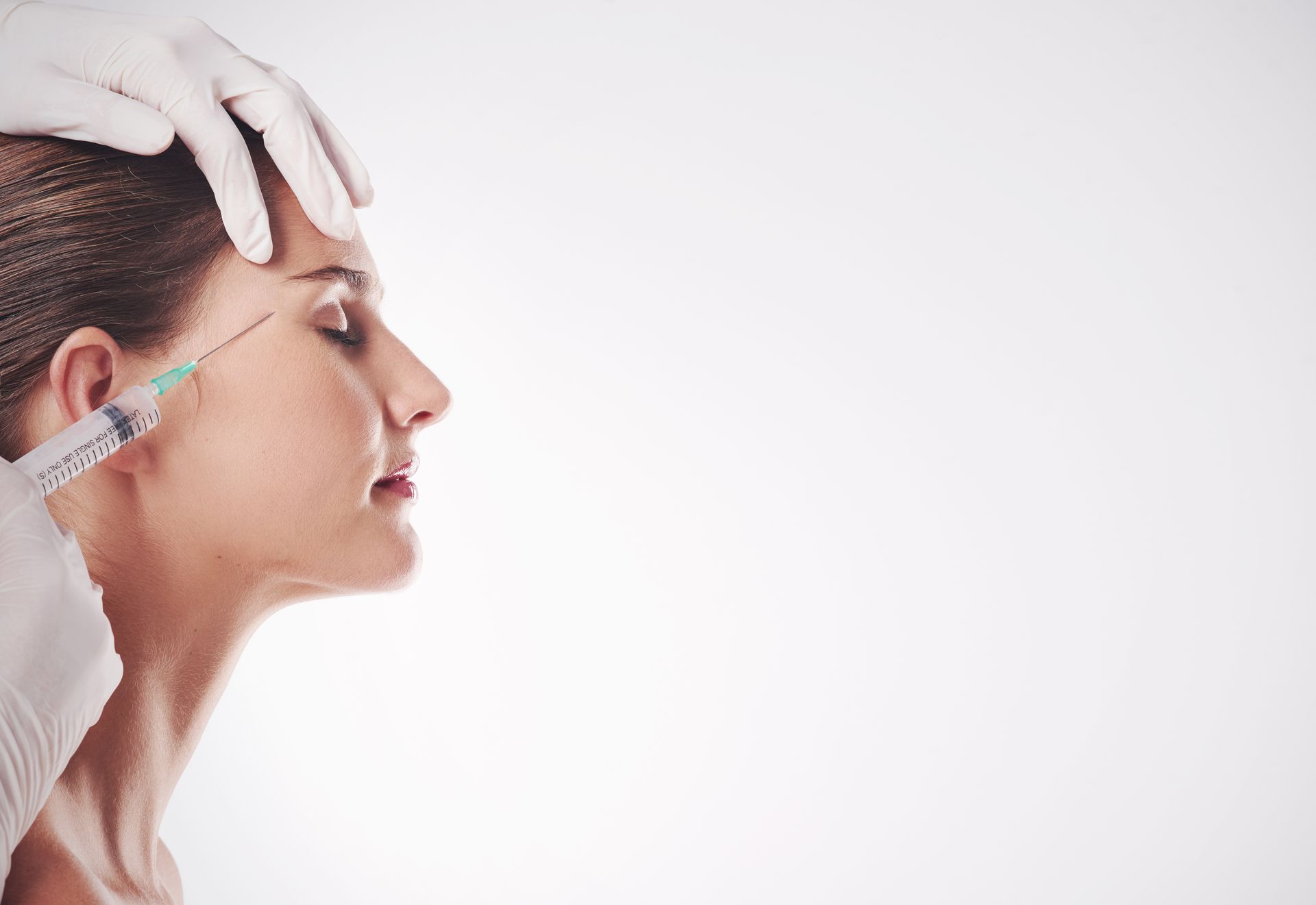 A woman is getting a botox injection in her forehead.