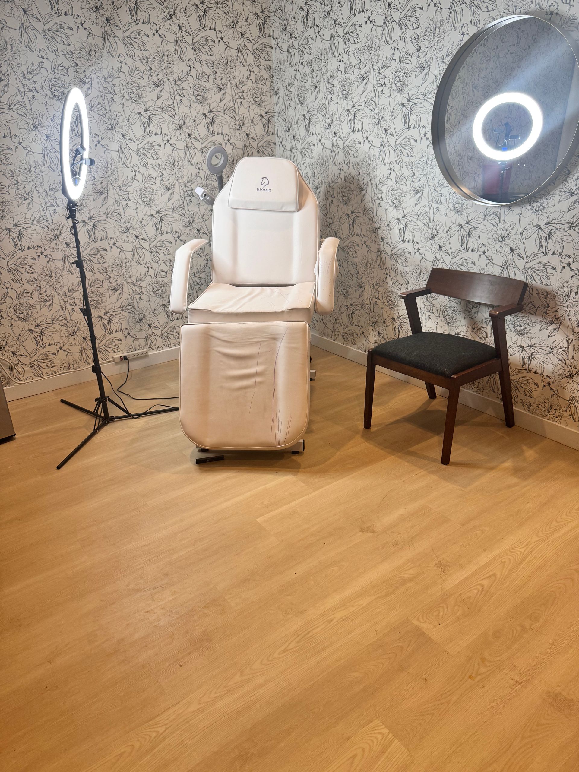 There is a chair and a ring light in the room.