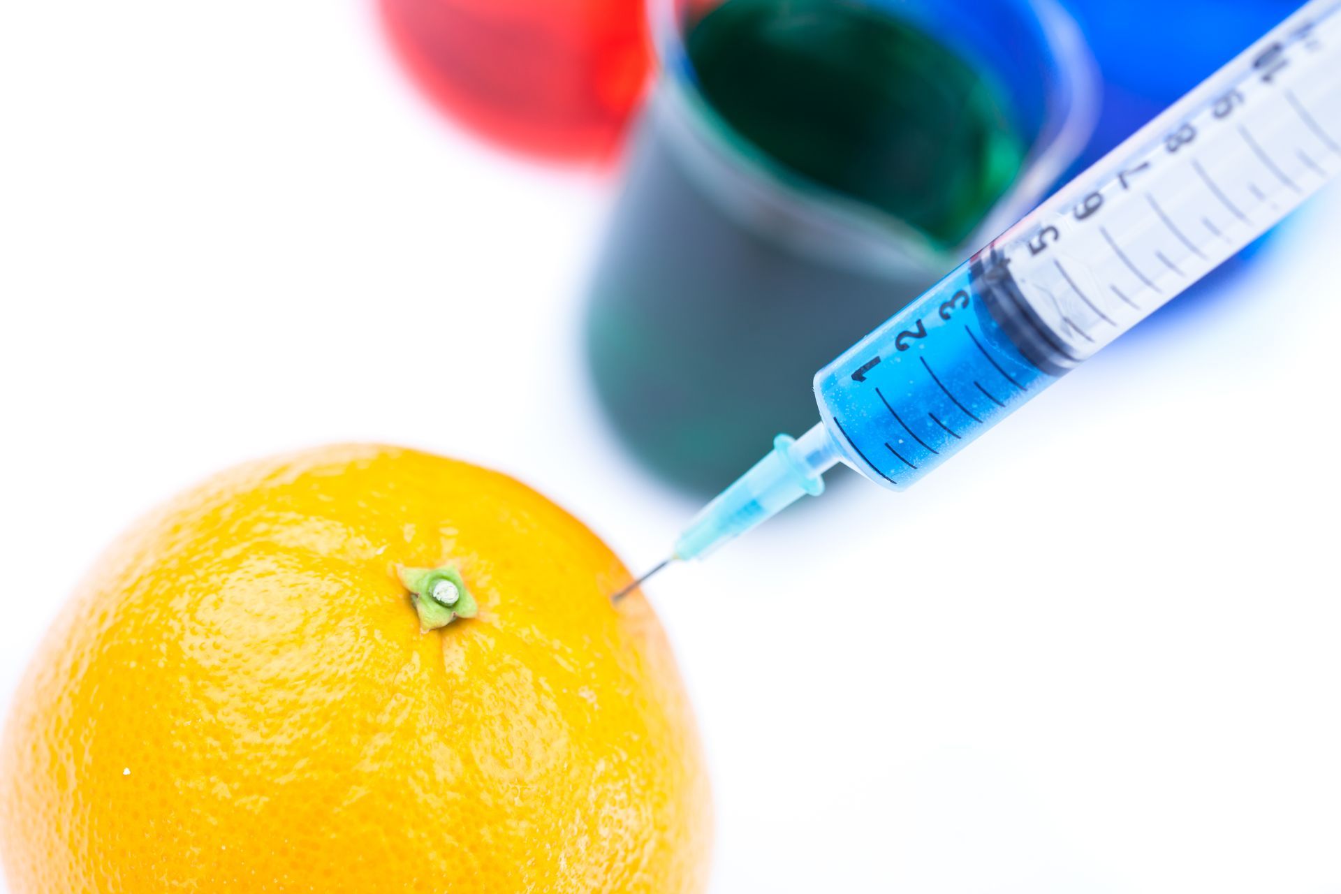 A syringe is being used to inject an orange