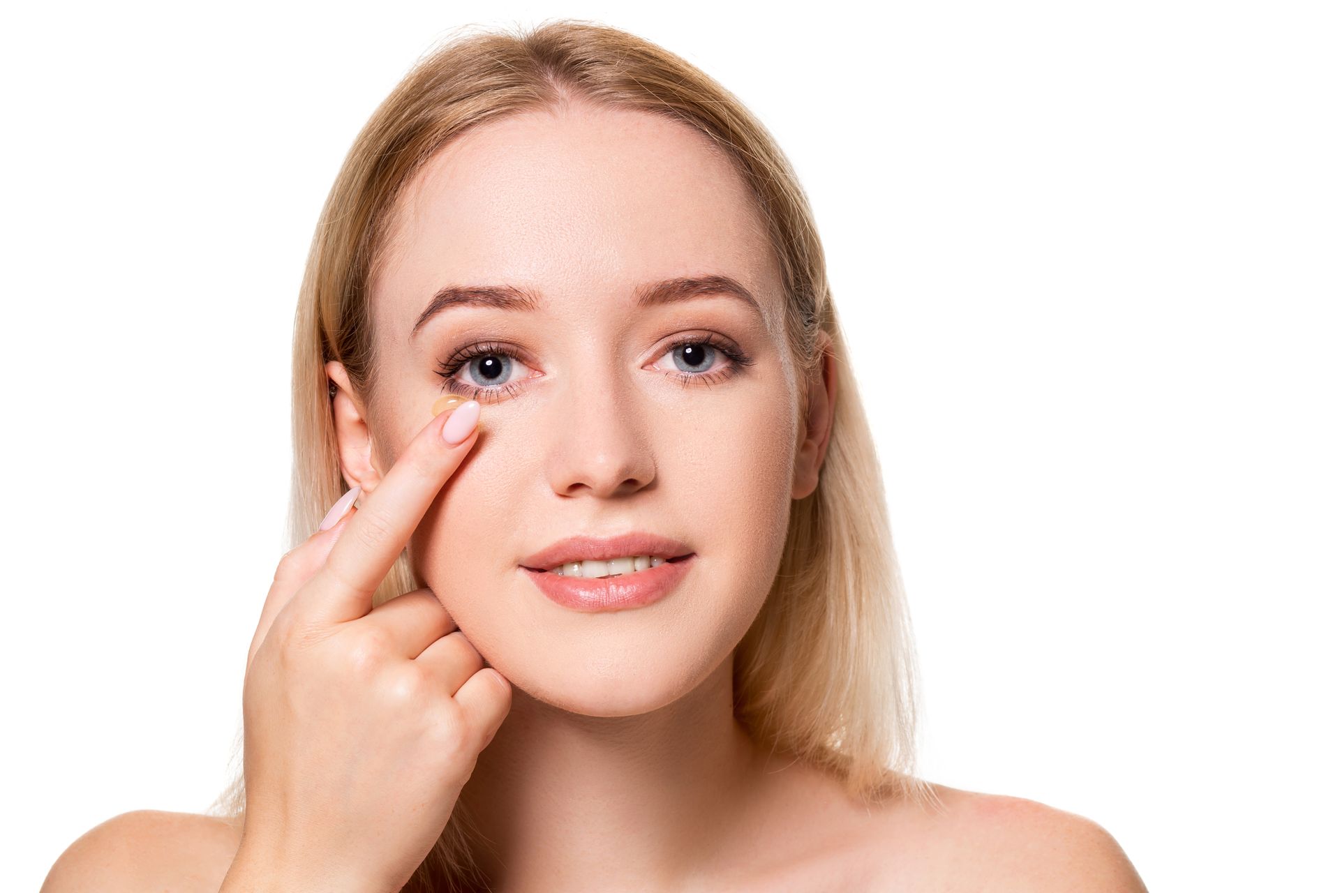 A woman is touching her face with her finger and smiling.