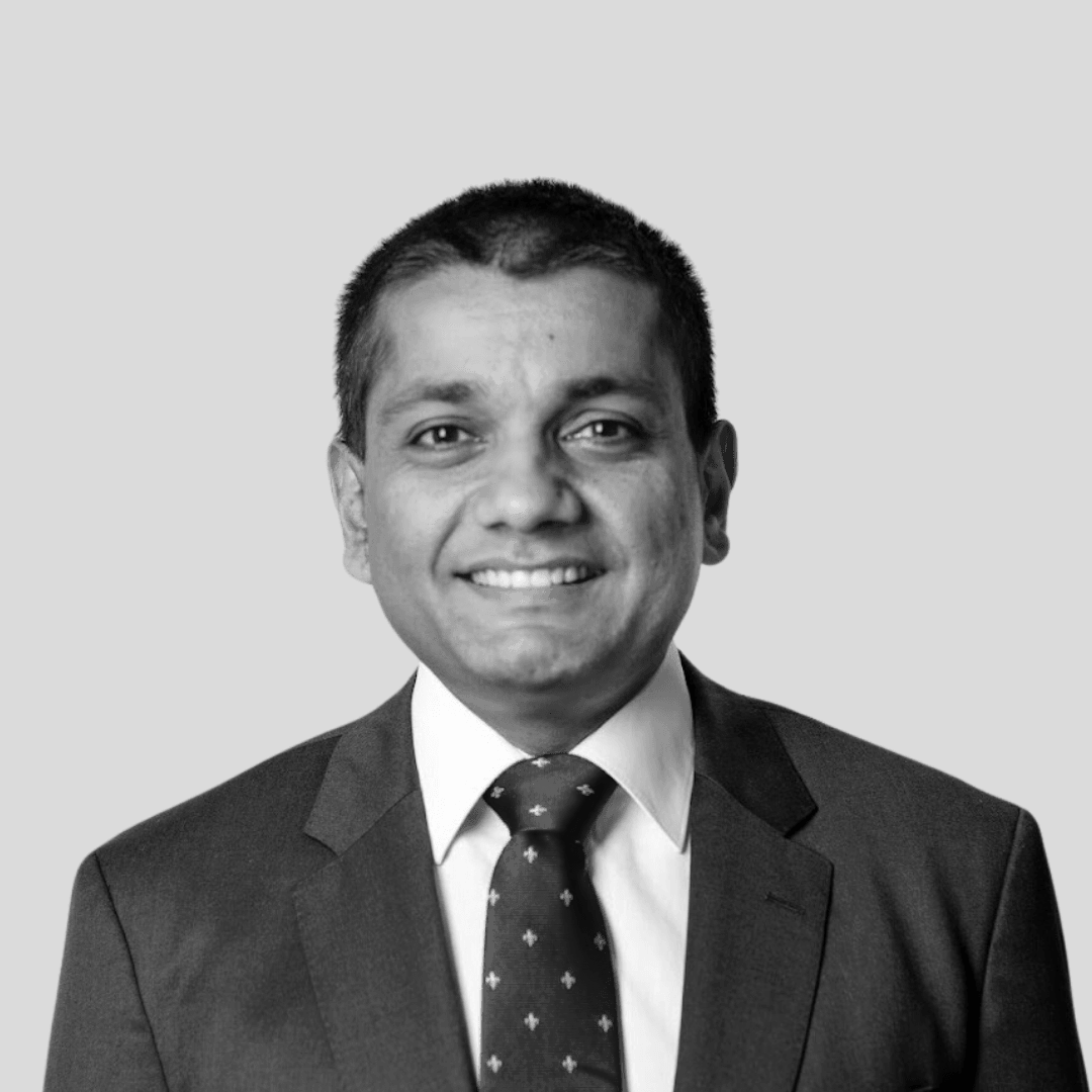Smiling man in a suit and tie, likely in a business or professional setting. Black and white headshot.