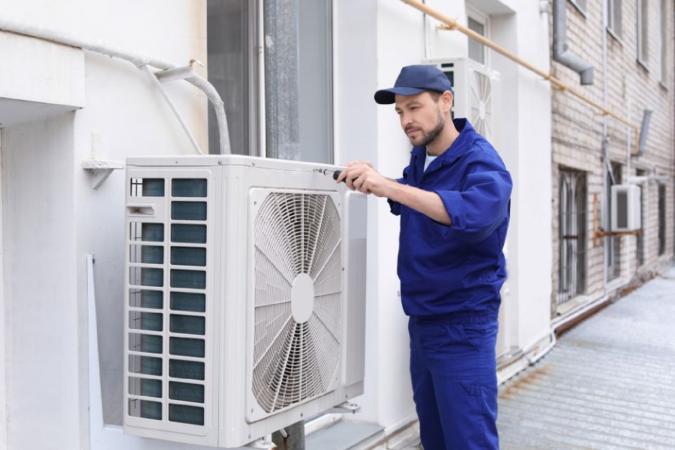 specialists repairing air conditioner outdoor unit