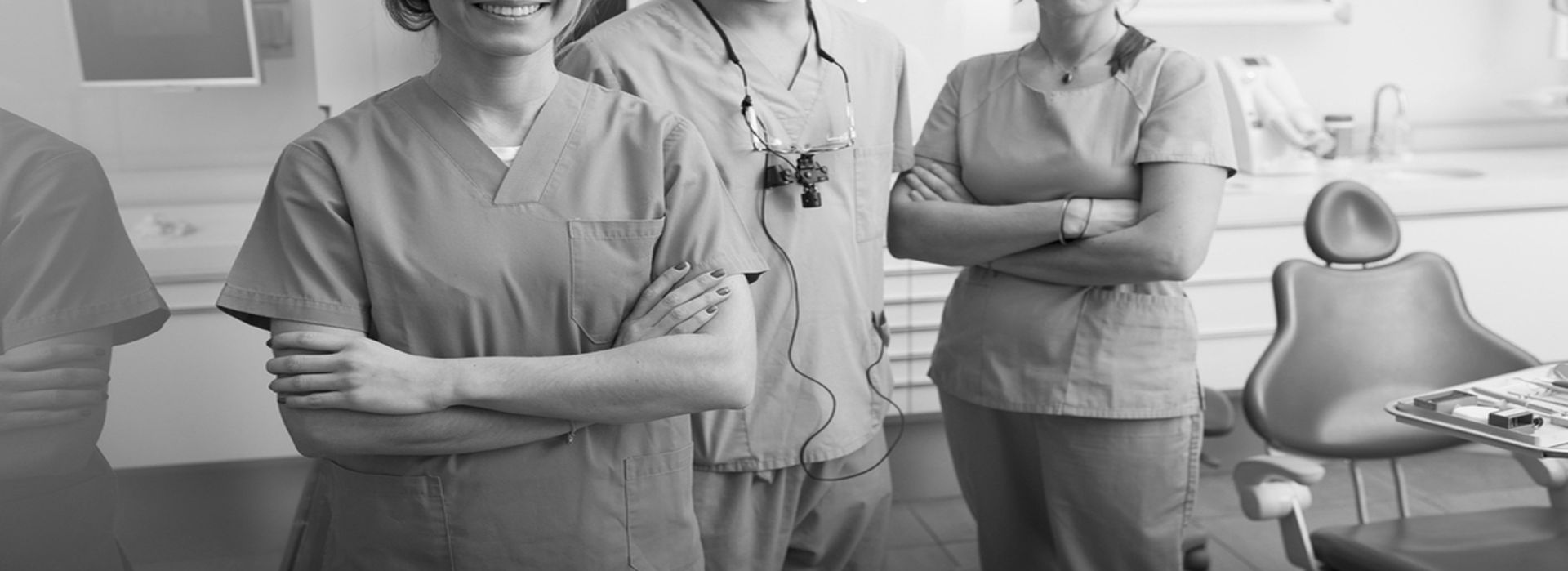 Eine Gruppe von Zahnärzten steht mit verschränkten Armen in einer Zahnarztpraxis.