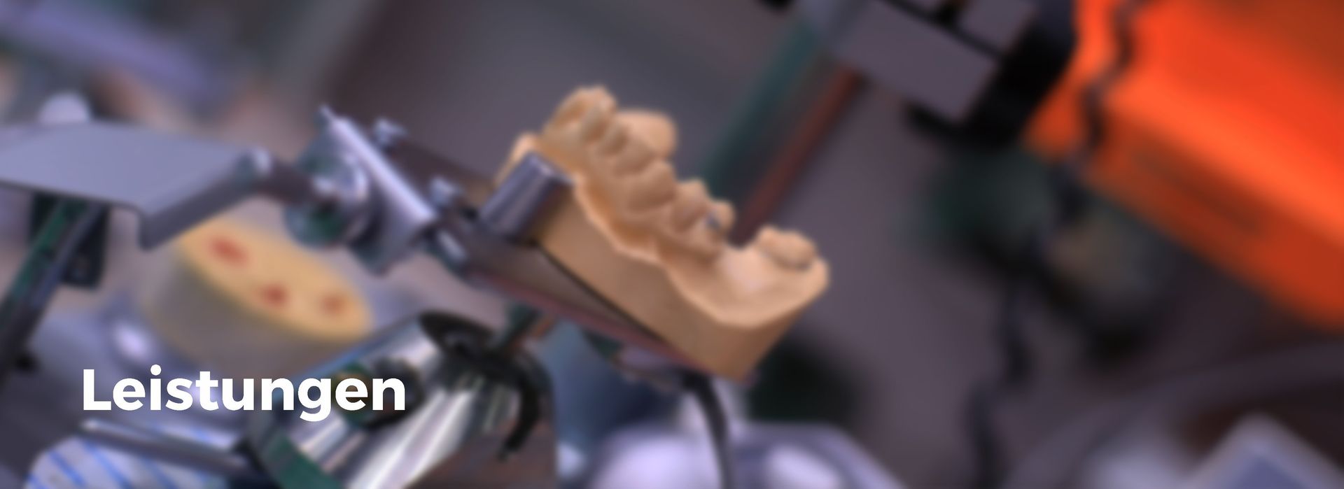 Eine Nahaufnahme eines Zahnmodells mit den Worten „Leistungen“ in der Ecke