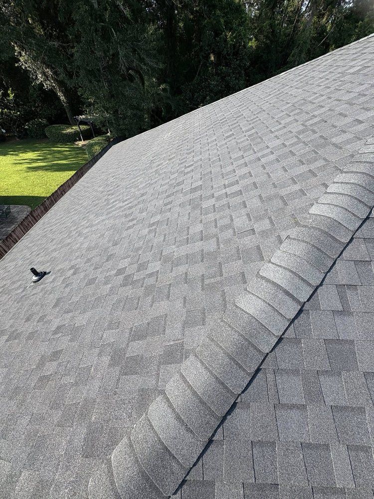 Gray asphalt shingle roof with a ridge and a vent pipe.