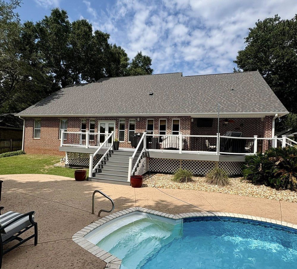Brick house with deck, stairs to backyard with pool. Overcast day.