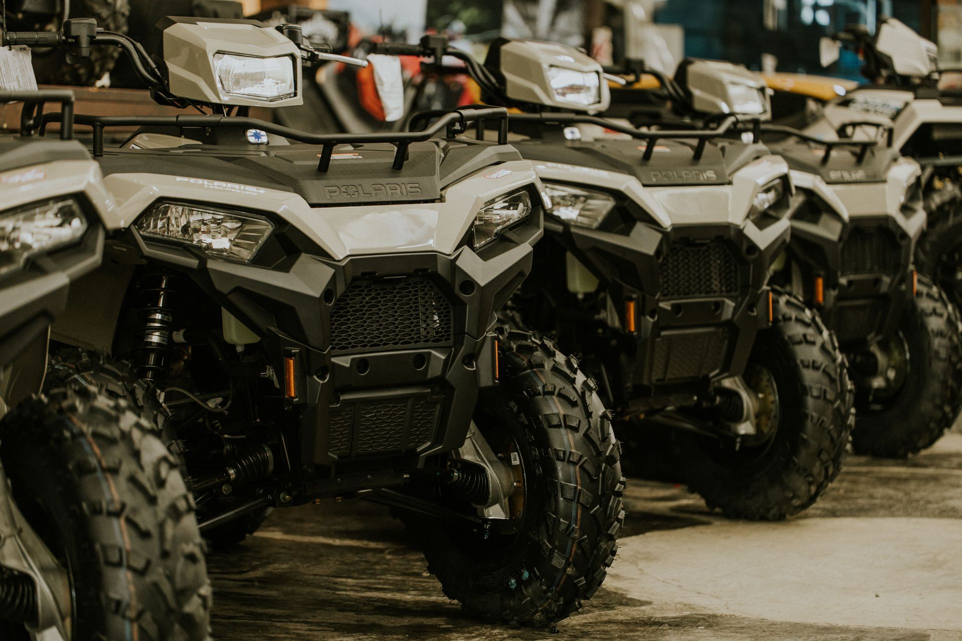 Row of gray all-terrain vehicles parked indoors at a dealership or showroom