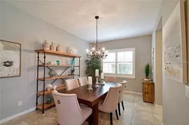Dining room with a wooden table, chairs, shelving, and a chandelier.