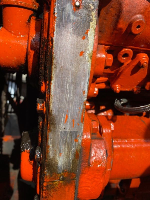 A close-up of a rusty orange engine on a tractor