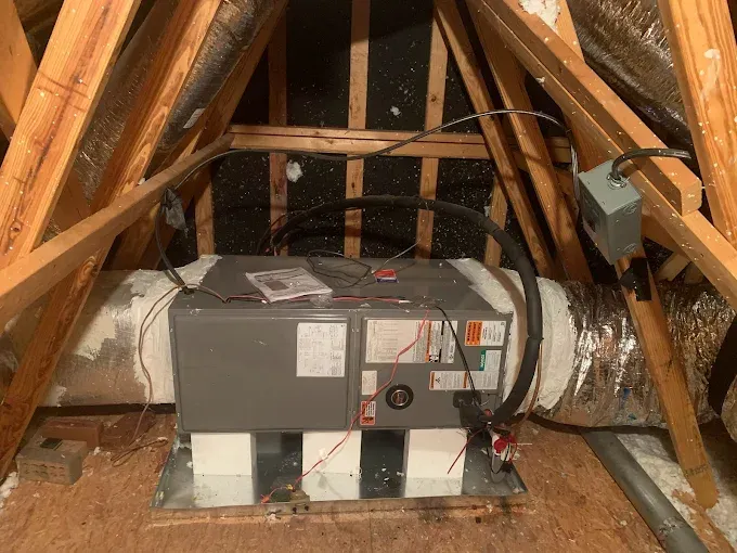 HVAC unit installed in an attic space, with ductwork and electrical connections visible.