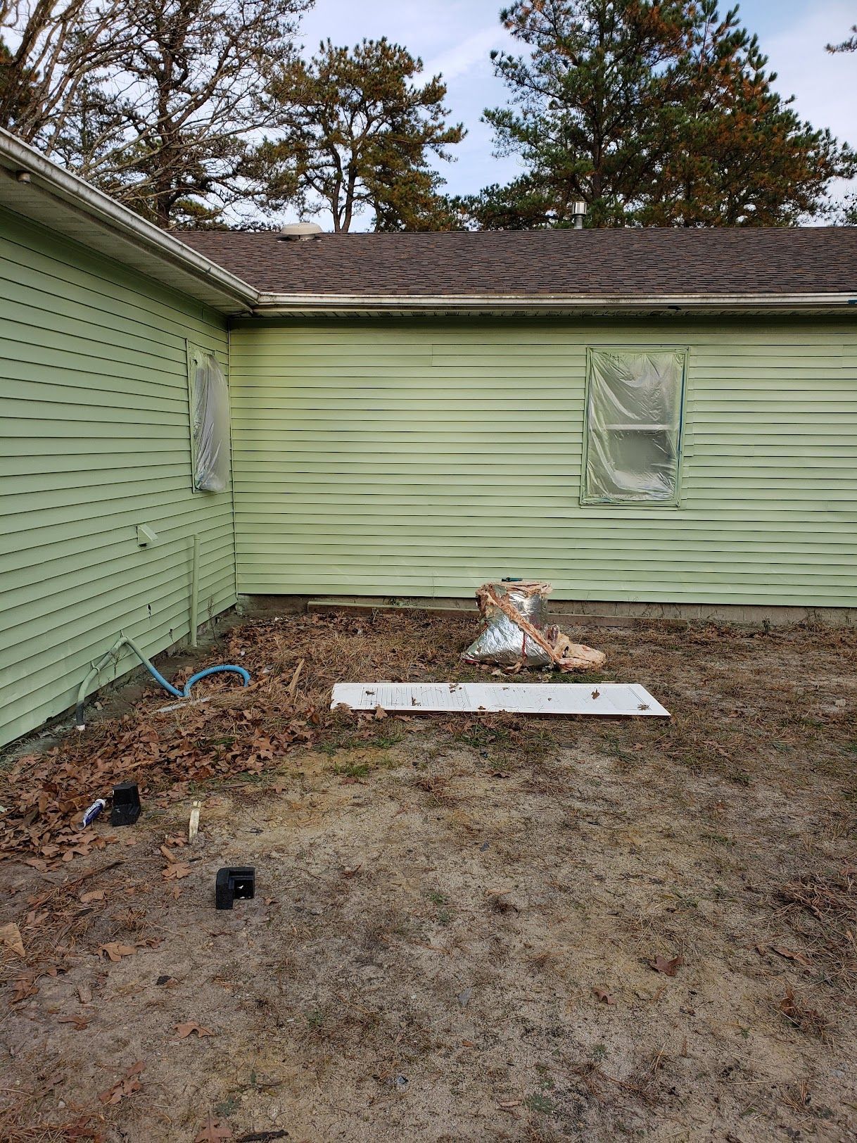 A green house is sitting on top of a dirt field.