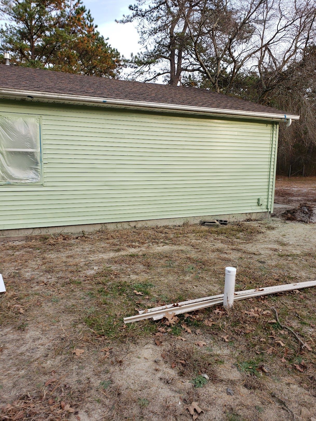 A green house is sitting in the middle of a dirt field.
