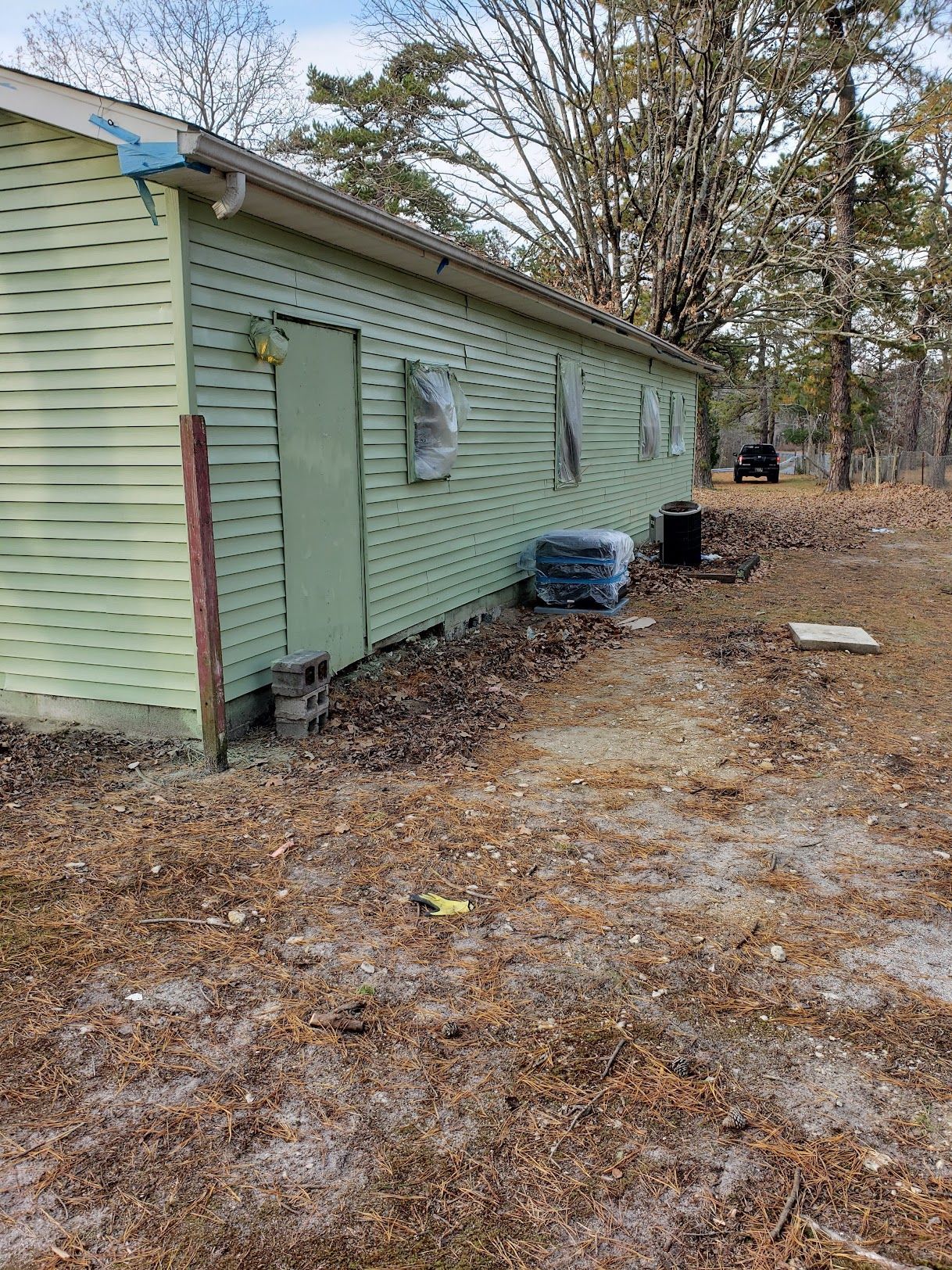 A green mobile home is sitting in the middle of a dirt field.