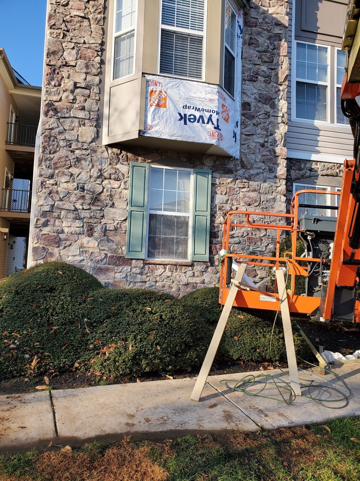 A crane is sitting on a sidewalk in front of a building.