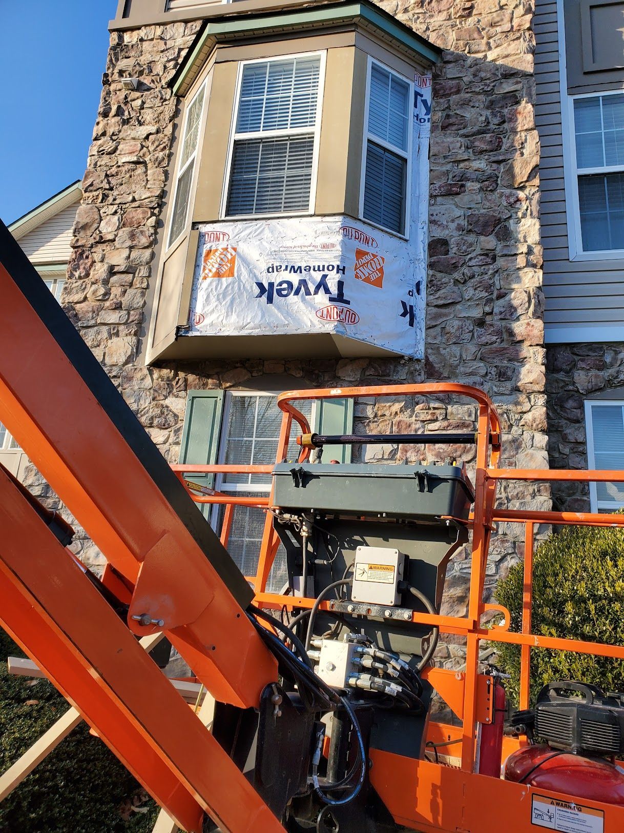 A crane is lifting a window with tyvek insulation on it.