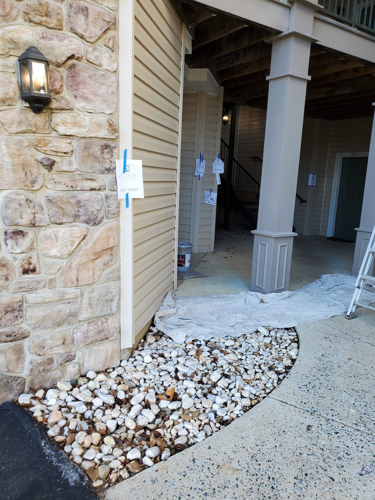 A building with a lot of rocks in front of it is being painted.