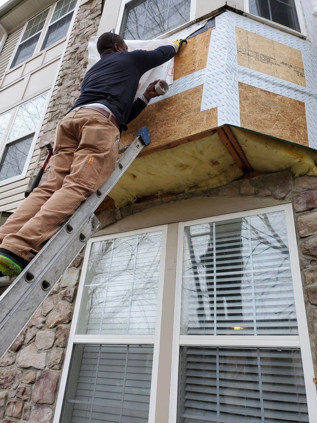 A man is standing on a ladder on the side of a building.
