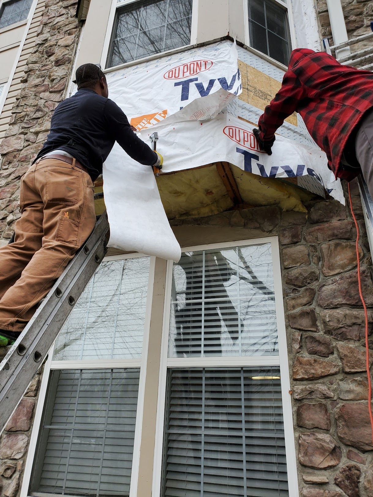 Two men are working on the side of a building.