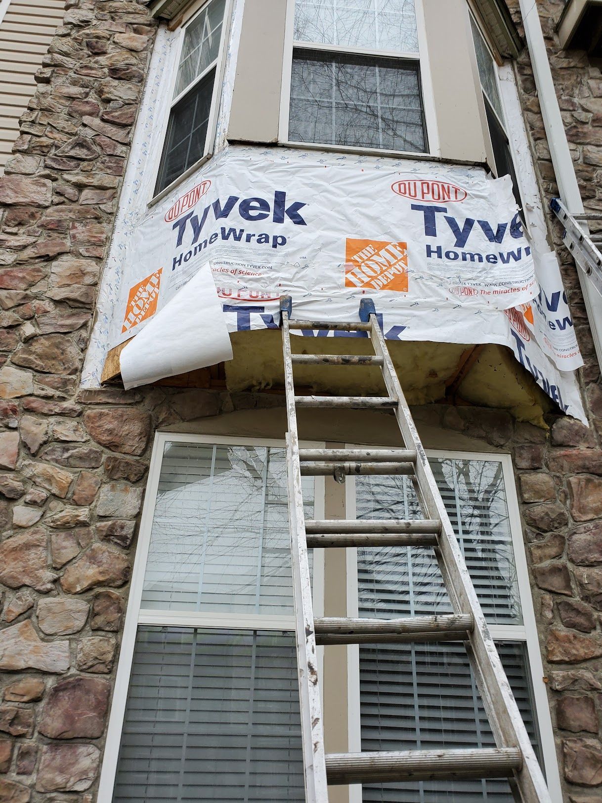 A ladder is sitting on the side of a building next to a window.