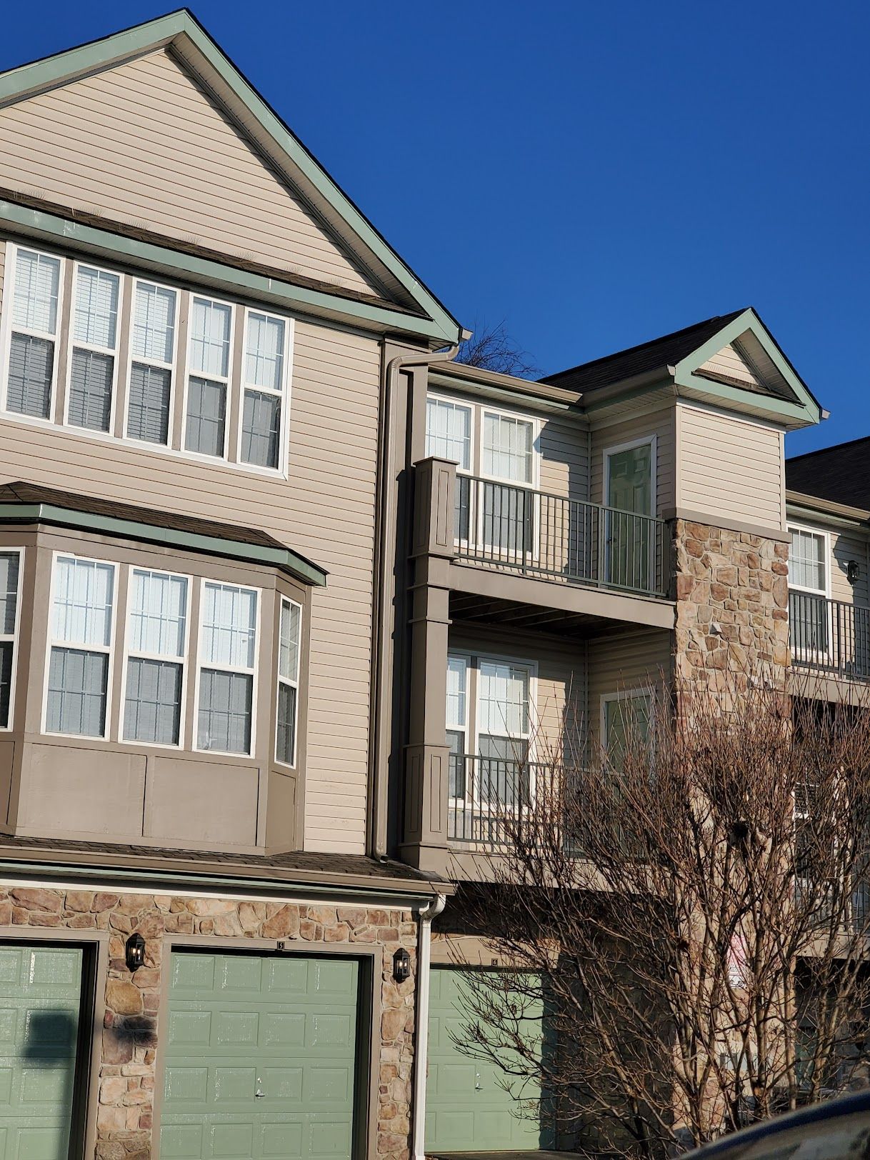 A large house with a balcony and green garage doors