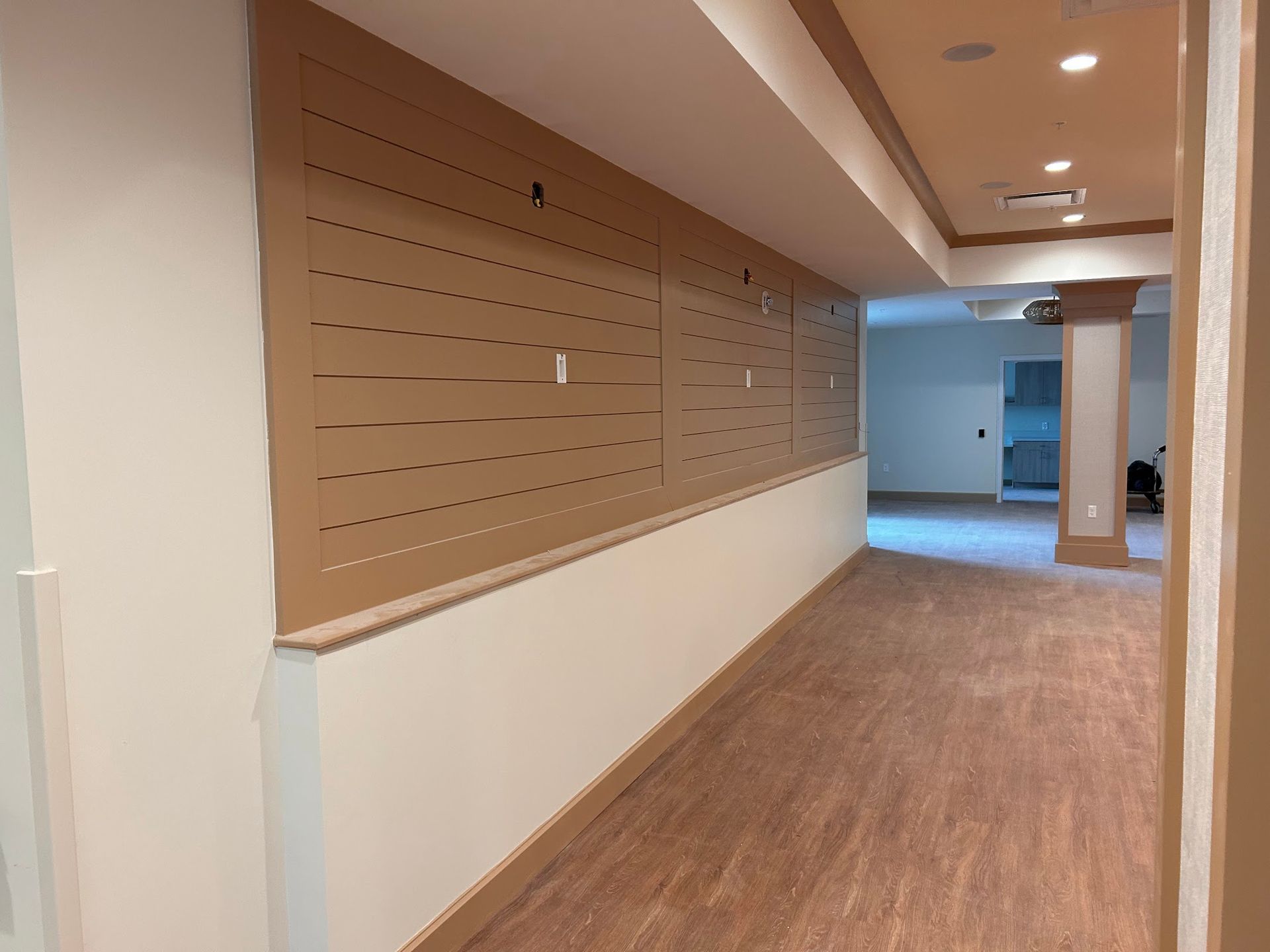 A long hallway with a wooden floor and a wall with holes in it