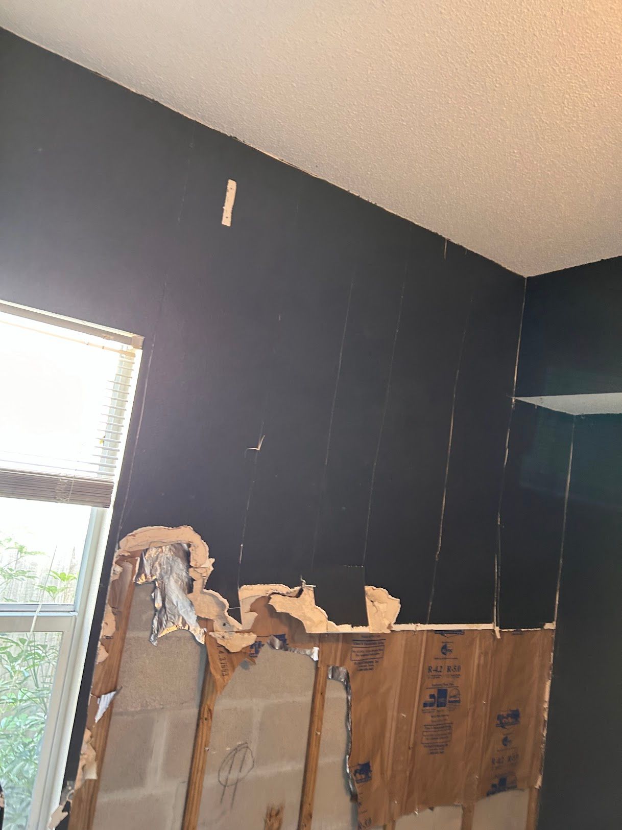 A room with a hole in the wall and a window.