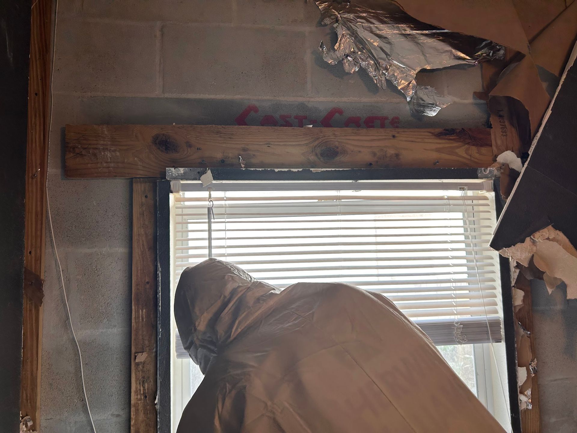 A man in a hooded jacket is looking out a window