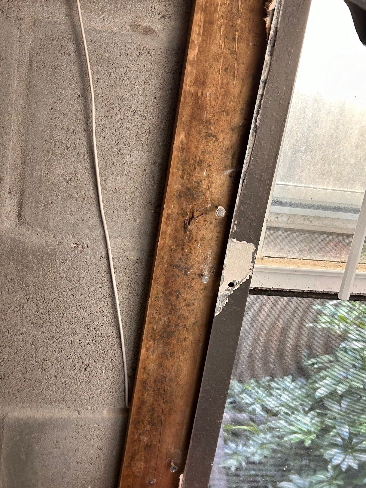 A close up of a wooden beam next to a window.