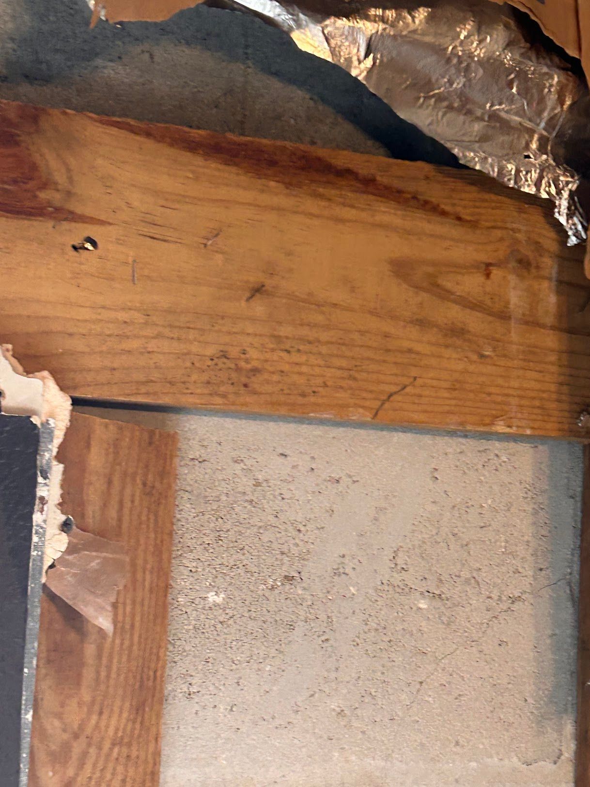 A piece of wood is sitting on top of a piece of aluminum foil.