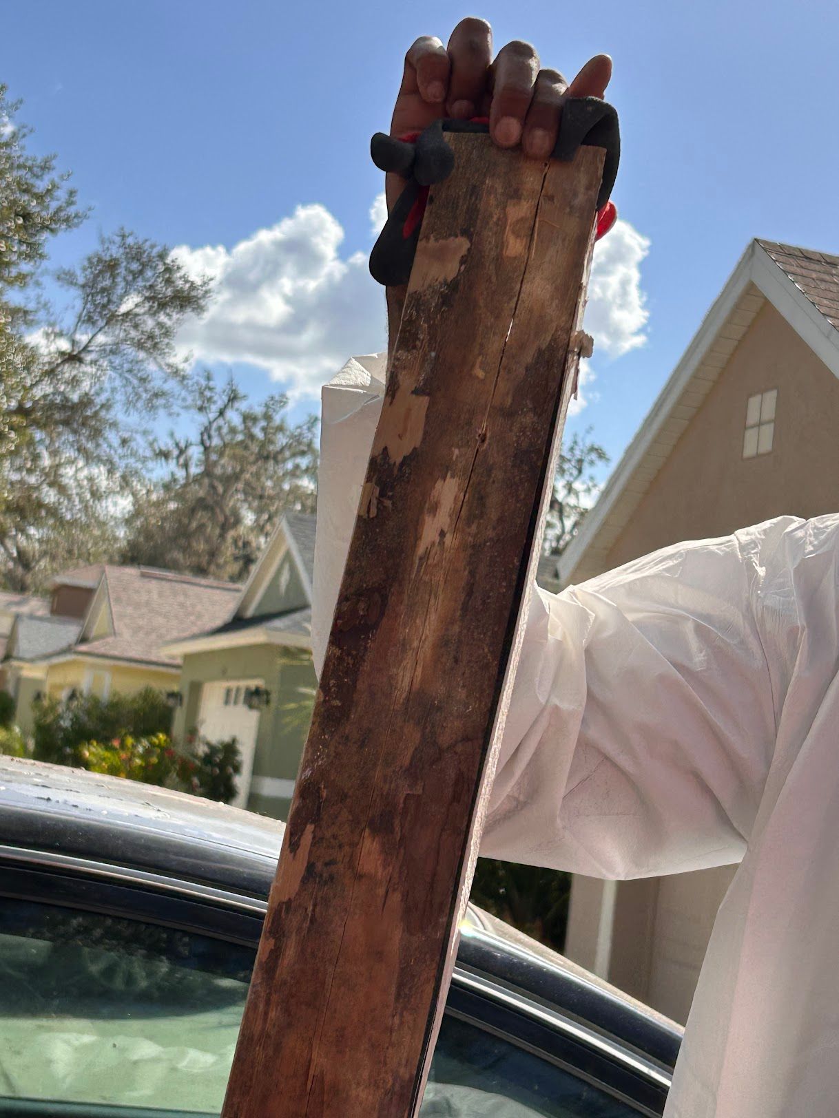 A person is holding a piece of wood in front of a car.